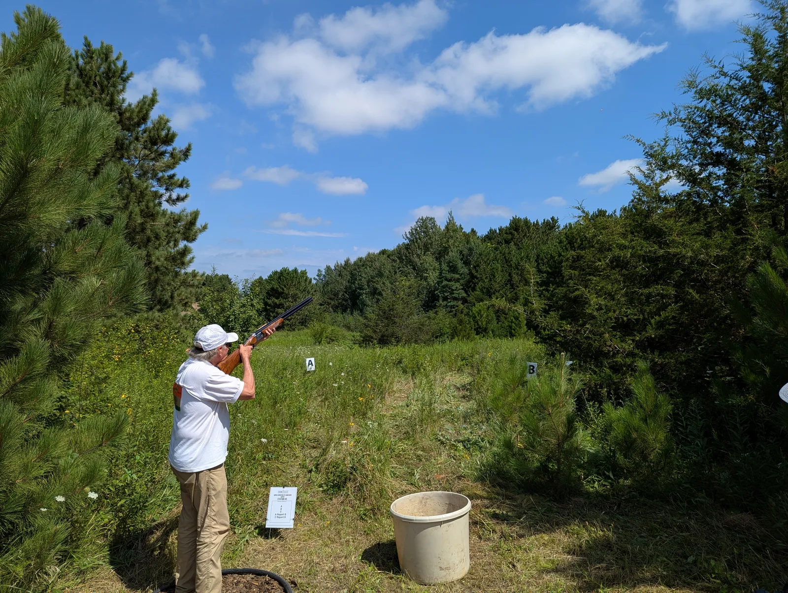A clay shooter tracking a target at a wooded course